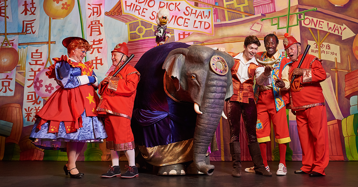 5 people in red pantomime costumes on stage with a pantomime elephant.