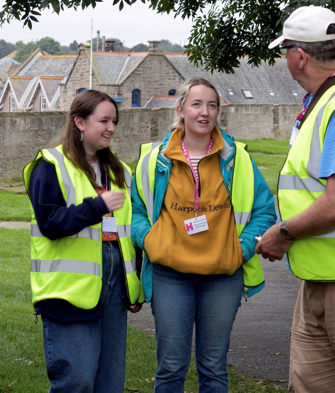 Three volunteers of varying ages chatting outside in high vis jackets