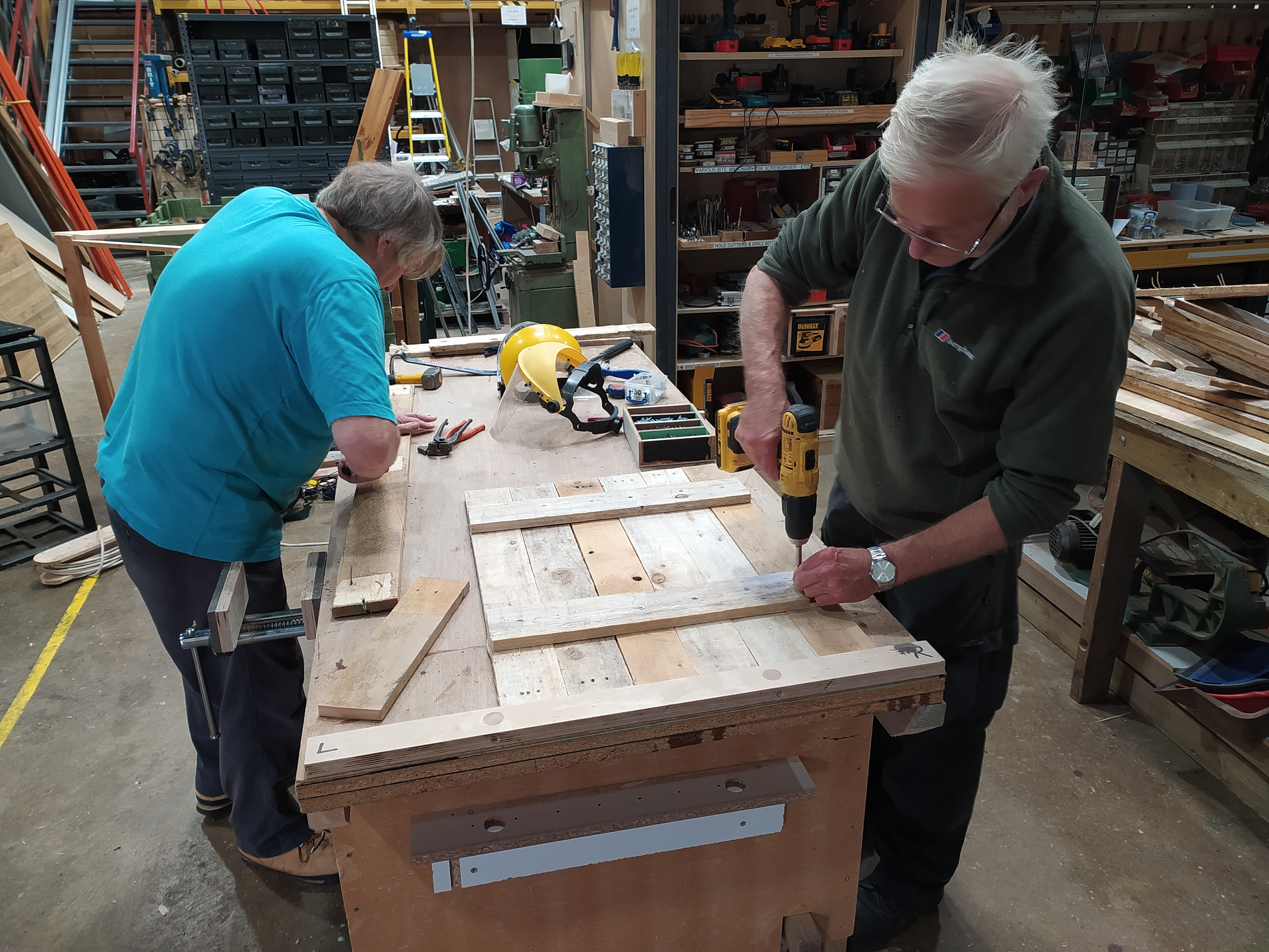 Two men doing carpentry at a workbench.