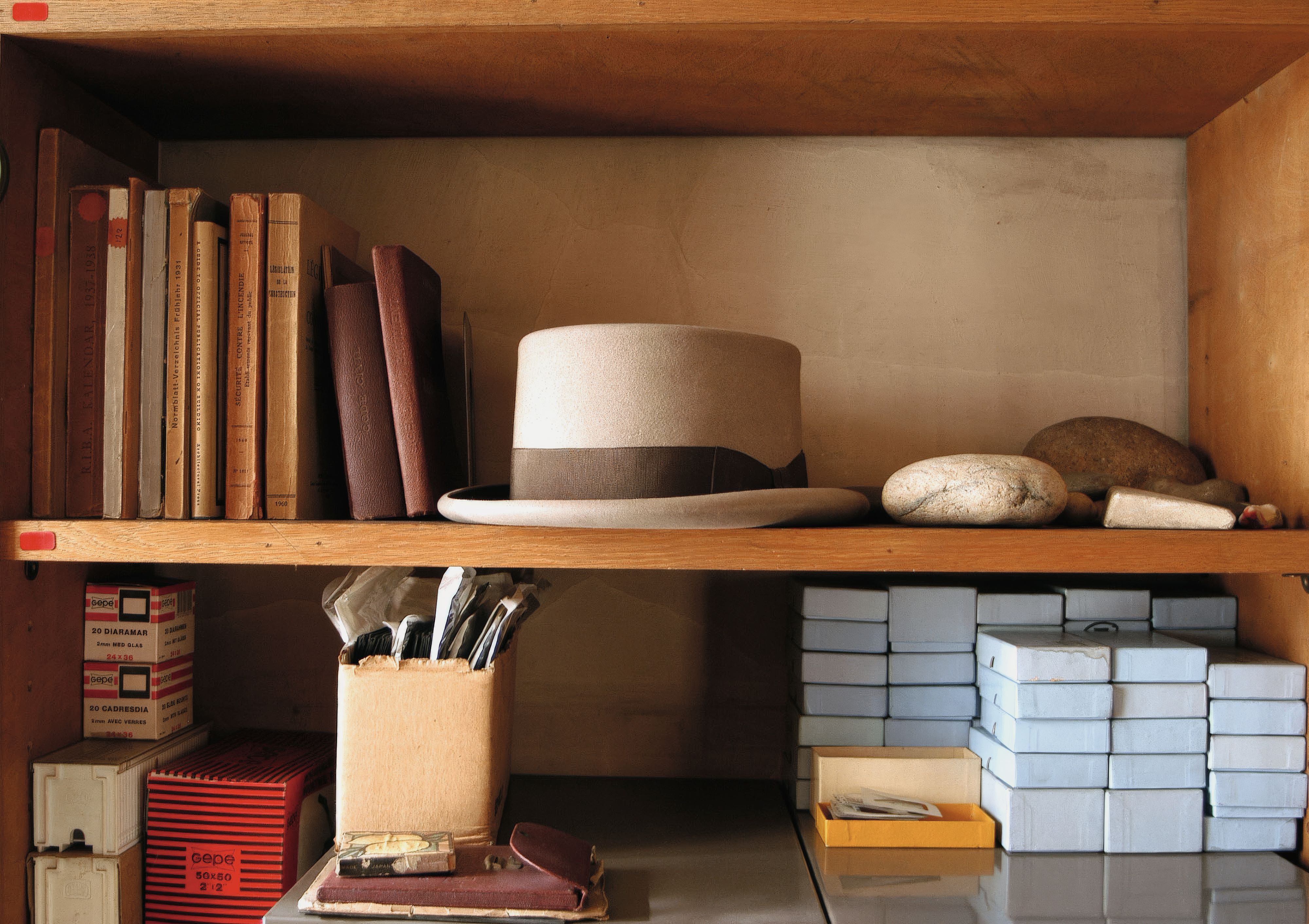 Elegant grey hat with black band sat in the middle of a set of shelves.