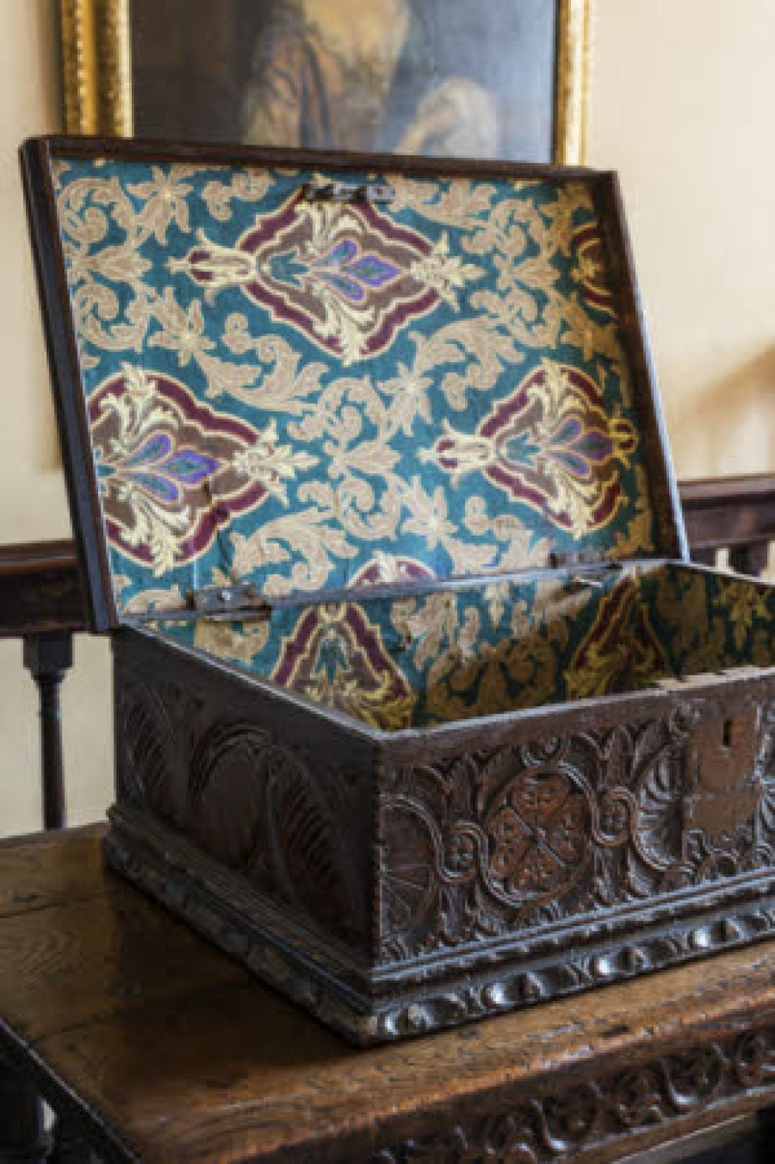 A dark wood, beautifully carved box, with patterned blue, red and white paper lining the box.