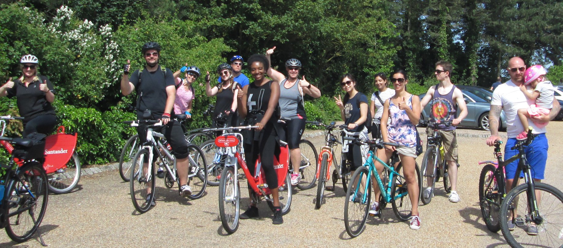 Large group of diverse people on bikes on a gravel path or road.