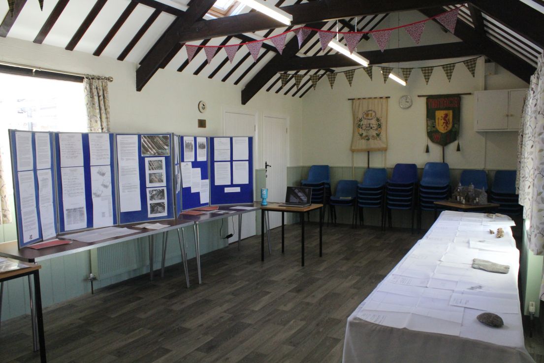Small hall with arched timber framed roof. Exhibition boards and tables along two walls, with chairs along the back wall