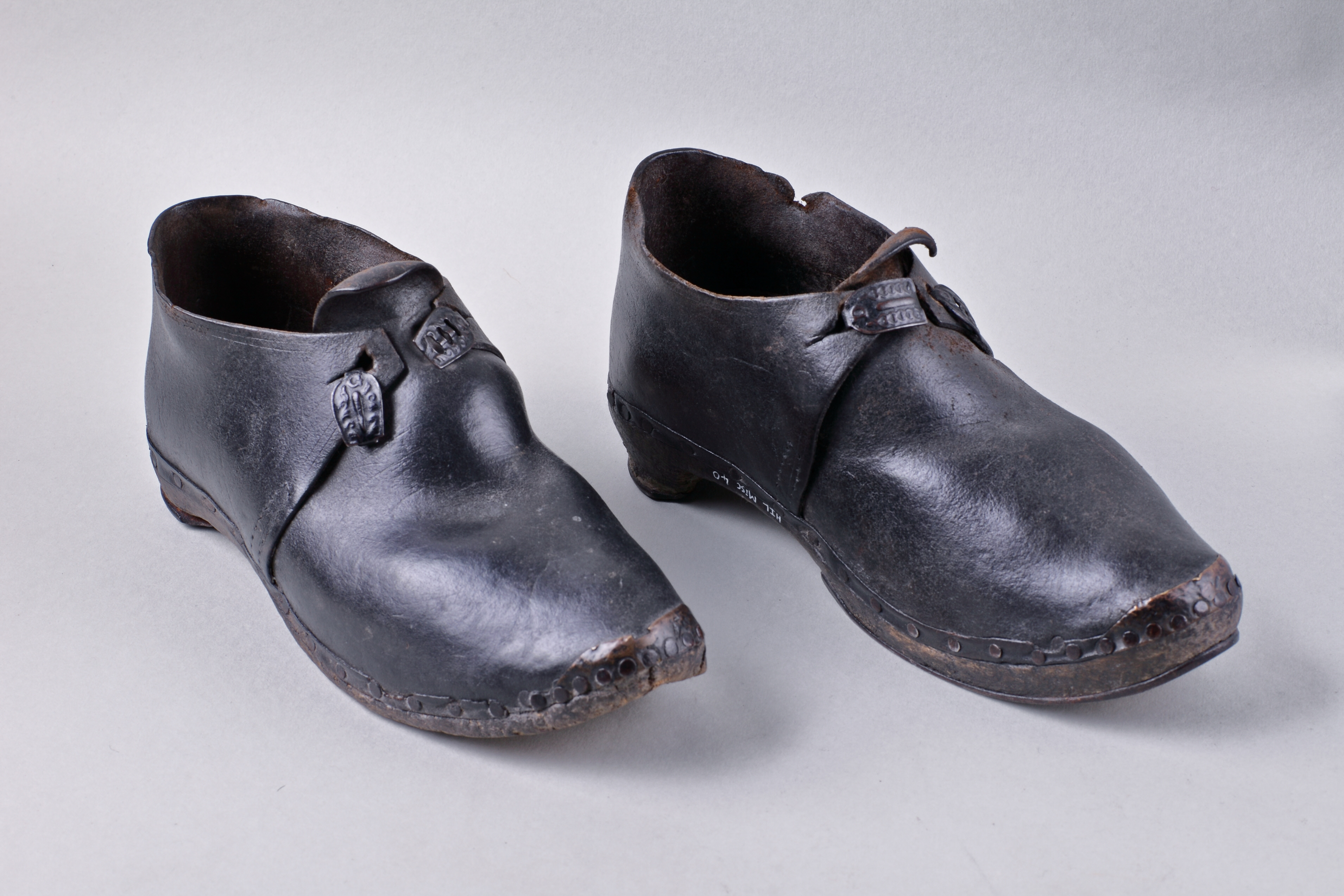 Pair of shiny, but worn black clogs.