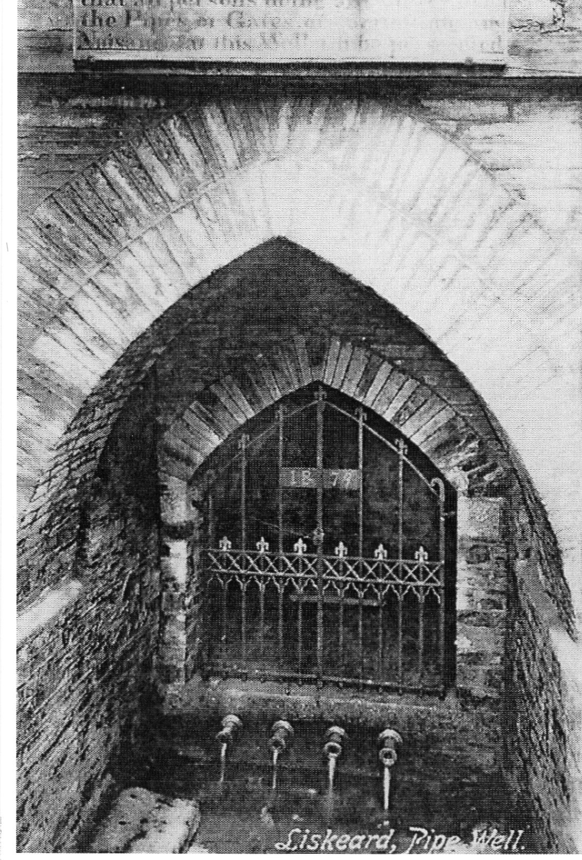 Old photograph of an arched brick well with water running out of a row of 4 pipes into a small basin.