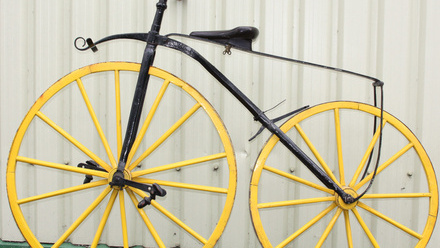 Old bicycle with black frame and yellow wheels.