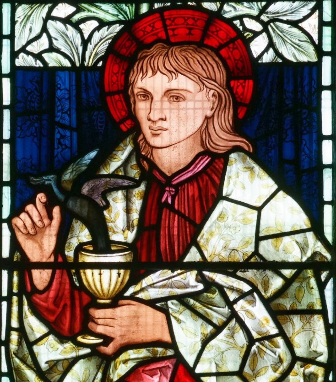 A stained glass window of a Saint, with a dragon immerging from a gold chalice.