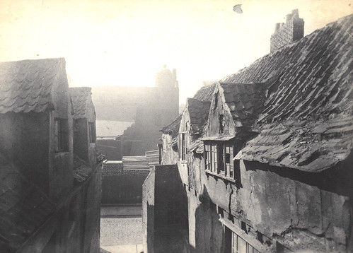 Old photograph of a narrow street with dilapidated houses.