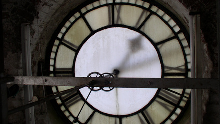 The back face of a large town clock revealing the cogs that are used to make it tick.